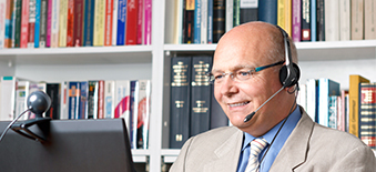 A man on the computer with his headset on